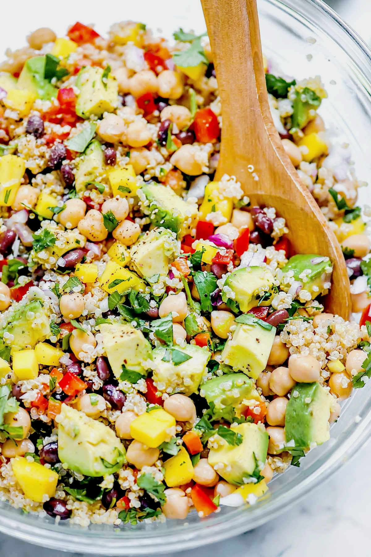 A Quinoa Salad with Chickpeas and Avocado in a bowl with a spoon to serve