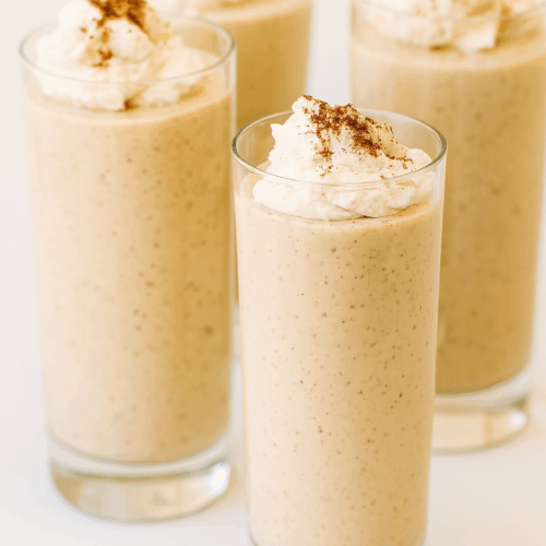 Creamy low carb spiced eggnog mousse served in a tall glass cup, topped with whipped cream and sprinkled with cinnamon, festive sugar-free holiday dessert.