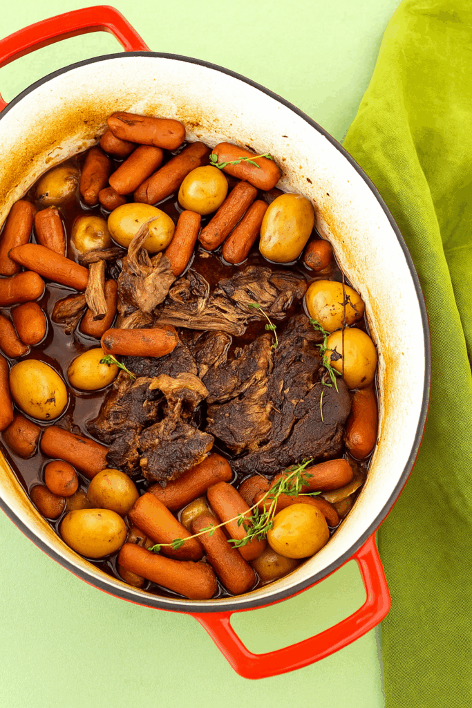 High-protein pot roast with tender beef chunks, carrots, and potatoes in a rich savory broth, served in a rustic bowl, perfect healthy comfort meal