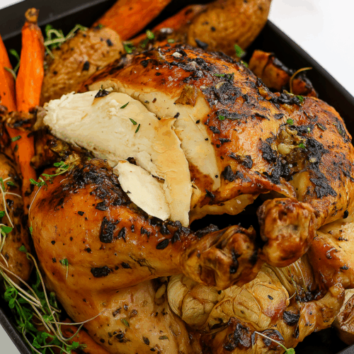 Close-up of juicy lemon herb roasted chicken with fresh rosemary and garlic, glistening with butter and citrus glaze.