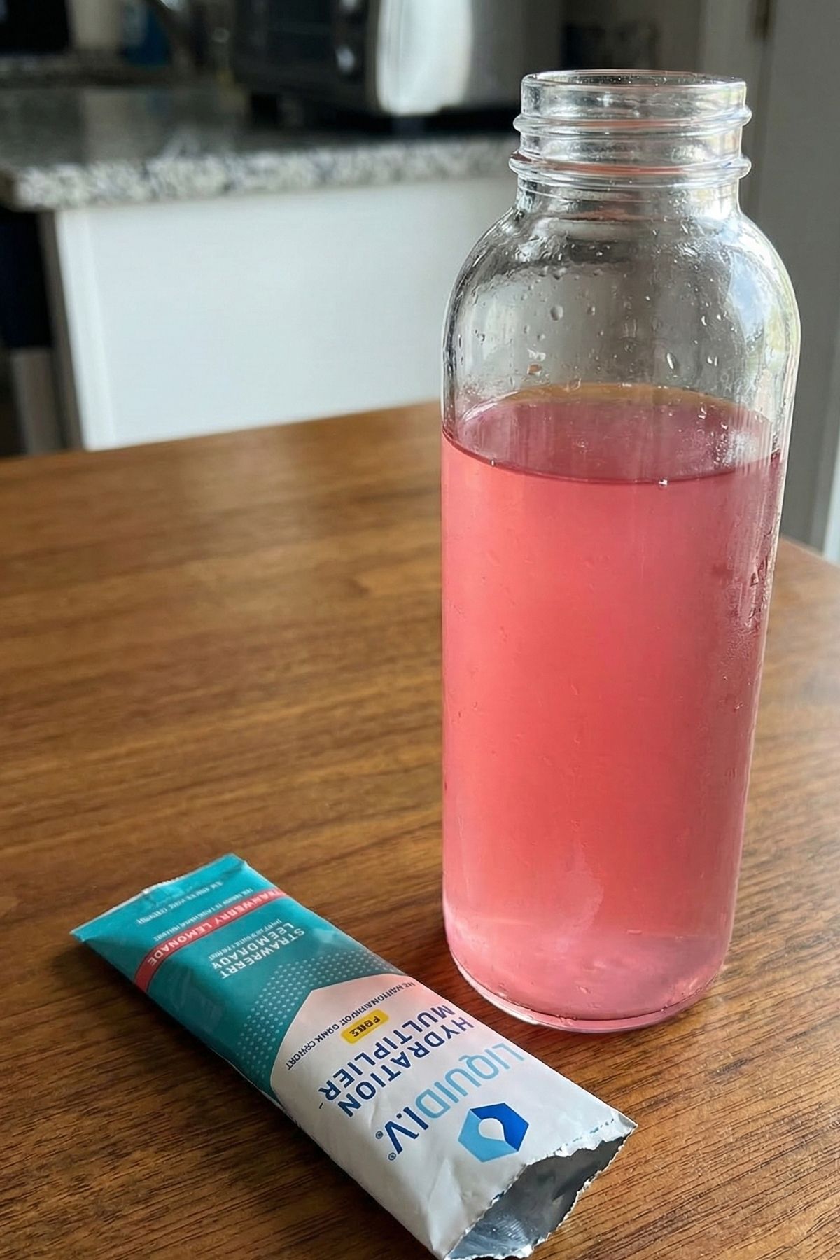 Liquid I.V. electrolyte powder packet next to a water bottle for preventing airplane dehydration and bloating.