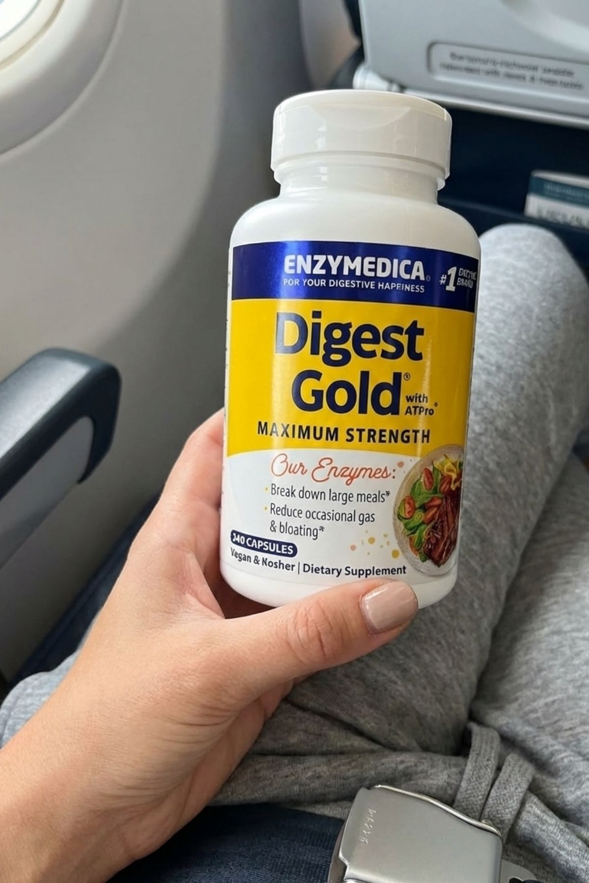 Woman holding Enzymedica Digest Gold digestive enzyme supplement to prevent gas and bloating after airplane meals.