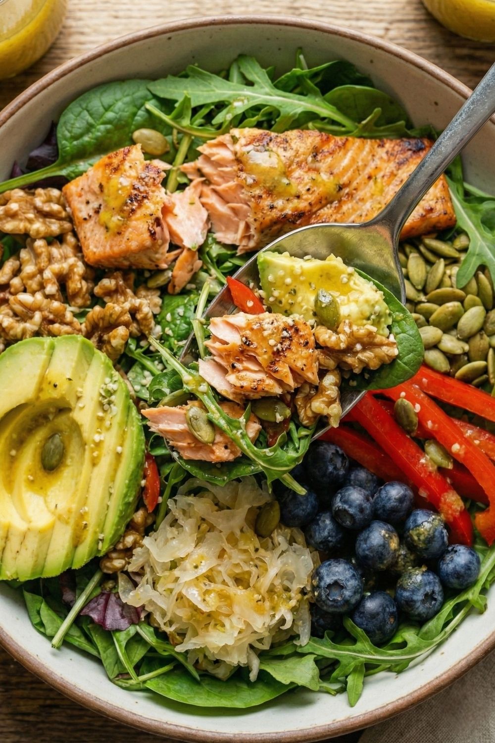 Pouring homemade "Liquid Gold" apple cider vinegar dressing over a healthy salmon and kale salad to support digestion.