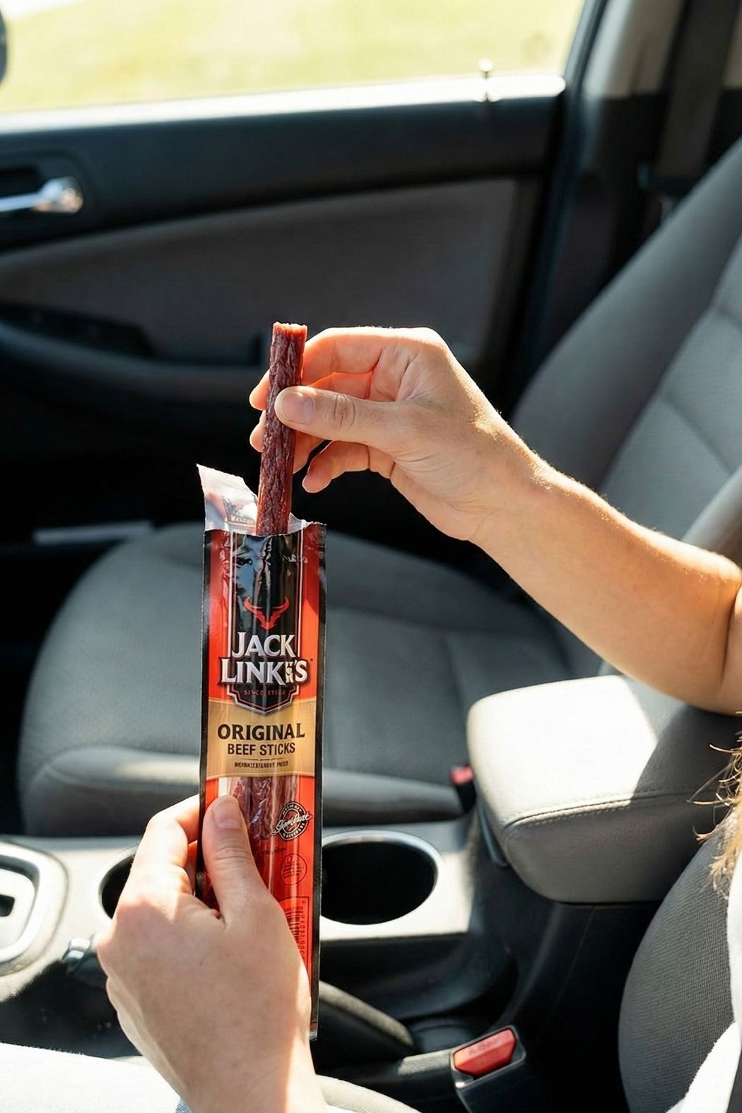 Close up of Jack Link's Zero Sugar beef jerky being eaten in a car as a high protein road trip snack idea.