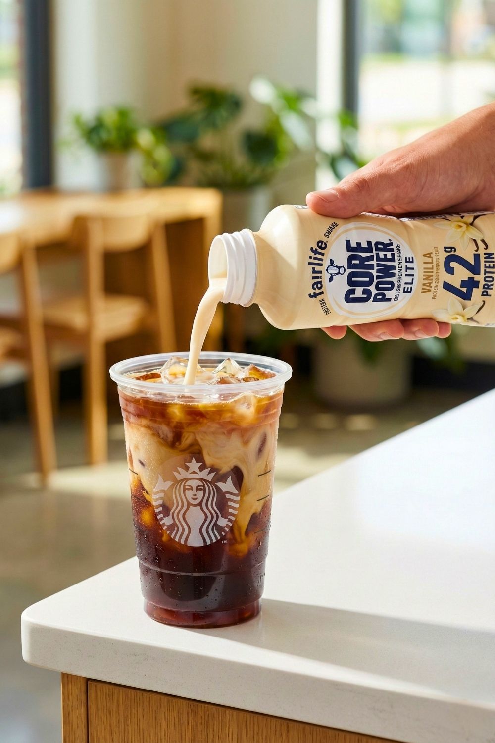 Close up of a gold straw swirling a low calorie vanilla iced latte with almond milk to mix the espresso.