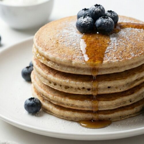 Pouring sugar-free syrup onto gluten-free protein pancakes, a low calorie breakfast option for weight loss.