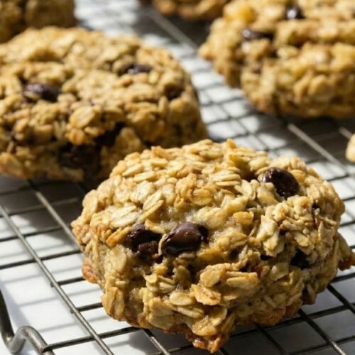 Stack of baked banana oatmeal cookies with one flipped upside down to show the perfectly flat, caramelized bottom surface achieved after baking for 10 to 12 minutes at 350 degrees Fahrenheit.