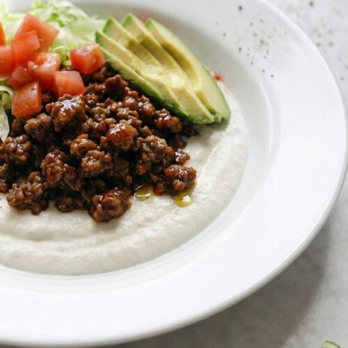45-degree angle macro shot focusing on the boundary where juicy taco meat meets the cool, creamy whipped cottage cheese base.