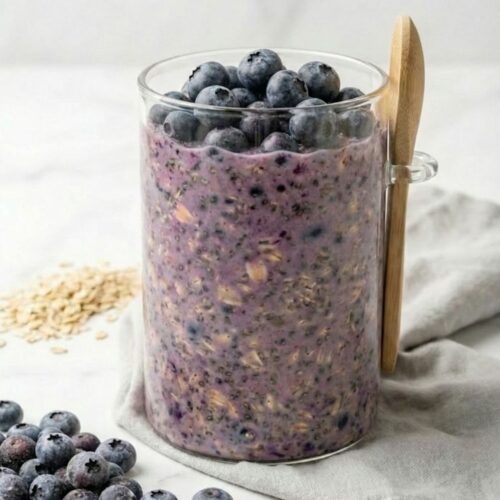 Overnight oats in 16oz borosilicate glass jar showing purple blueberry anthocyanin layer and white yogurt cap for anti-inflammatory breakfast.