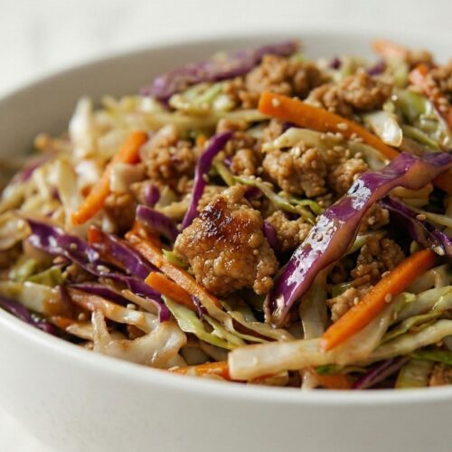 Extreme close-up of glossy turkey crumbles and tender-crisp cabbage showing moisture and sauce coating, focusing on savory texture.