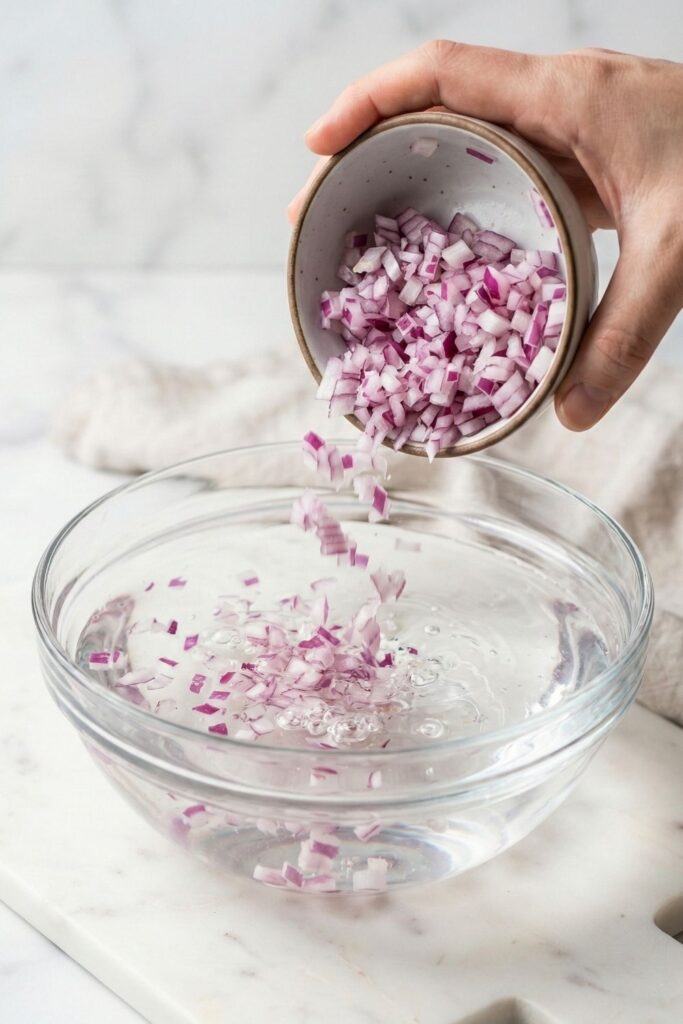 Exactly 1/2 red onion, finely diced and fully submerged in a small bowl of clear water to extract sulfur and mellow the flavor.